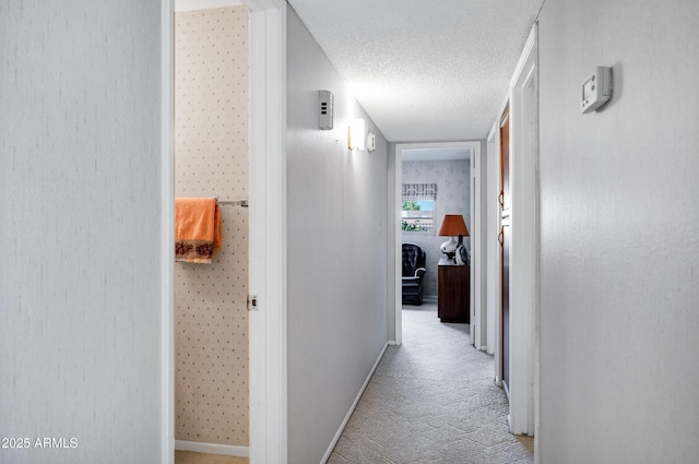 corridor featuring light colored carpet and a textured ceiling