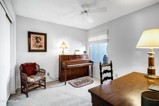 sitting room featuring light carpet, ceiling fan, and a textured ceiling