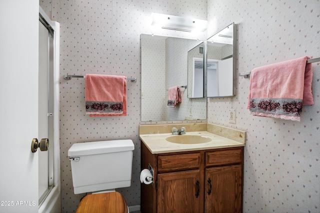 full bathroom with enclosed tub / shower combo, vanity, and toilet