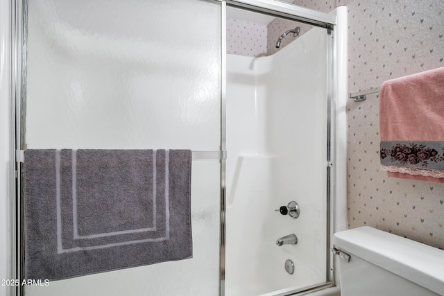 bathroom featuring combined bath / shower with glass door and toilet