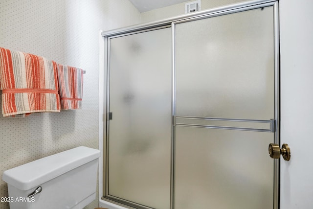 bathroom featuring toilet and a shower with shower door