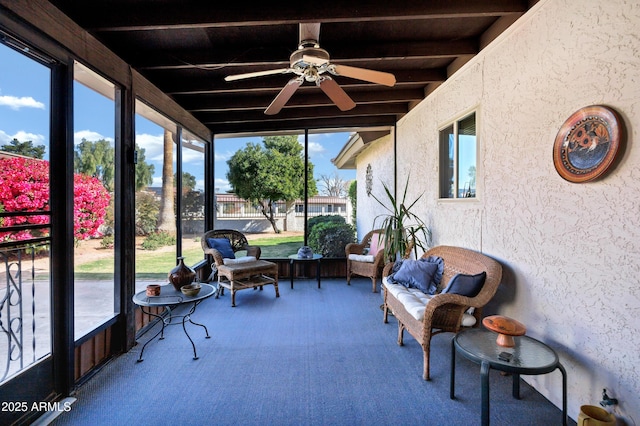 sunroom / solarium with beam ceiling and ceiling fan