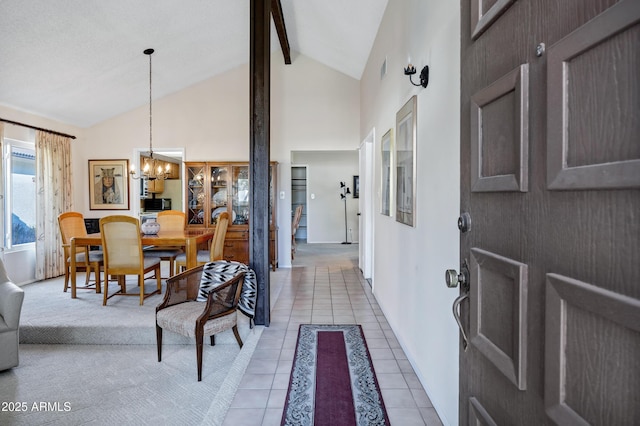 foyer entrance featuring beamed ceiling, a notable chandelier, high vaulted ceiling, and light tile patterned floors