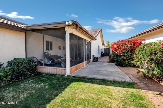 view of property exterior featuring a yard, a patio area, and a sunroom