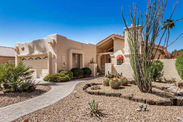 southwest-style home with stucco siding, fence, a gate, and a garage