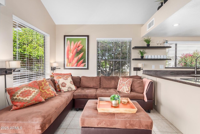 living area featuring visible vents, lofted ceiling, and light tile patterned flooring