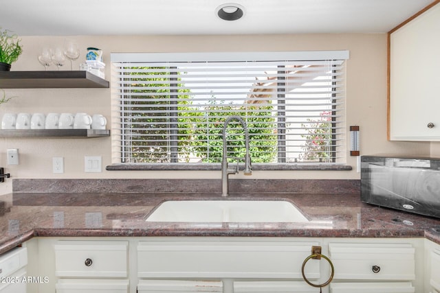 kitchen with a healthy amount of sunlight, white cabinets, white dishwasher, and a sink