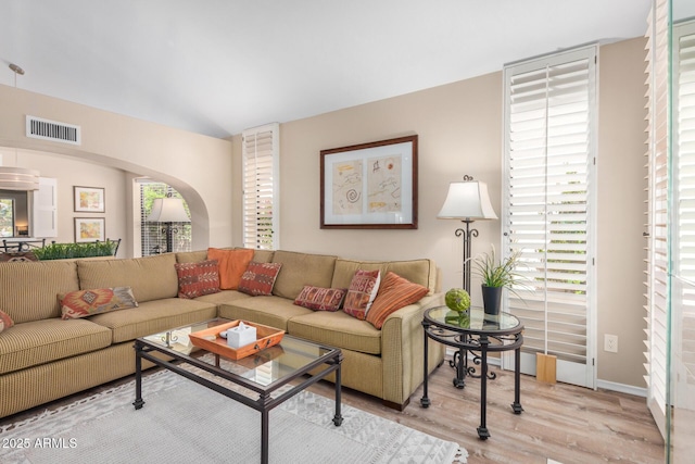 living room featuring visible vents, arched walkways, wood finished floors, and a wealth of natural light