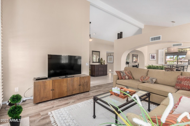 living room with arched walkways, visible vents, lofted ceiling with beams, and wood finished floors