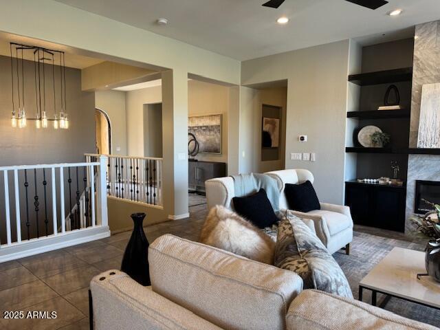 tiled living room with ceiling fan, a fireplace, and built in shelves