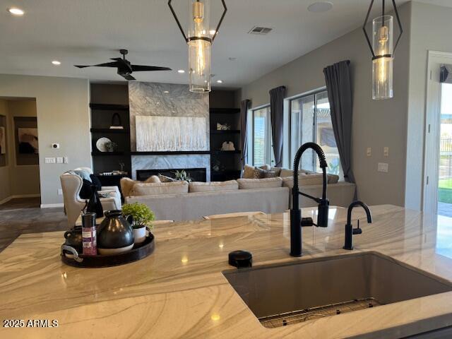 kitchen featuring ceiling fan, sink, a high end fireplace, and decorative light fixtures