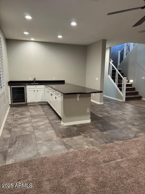 kitchen with sink, white cabinetry, a kitchen breakfast bar, wine cooler, and kitchen peninsula