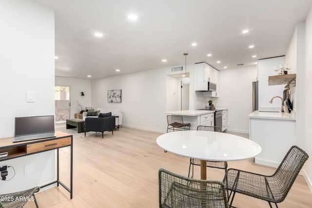 dining area with sink and light hardwood / wood-style floors