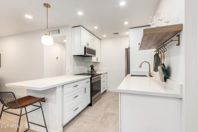 kitchen featuring sink, white cabinetry, appliances with stainless steel finishes, kitchen peninsula, and pendant lighting