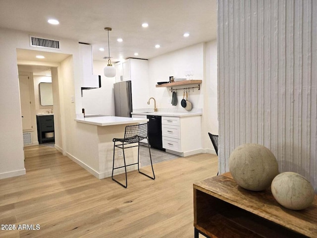 kitchen with white cabinetry, dishwasher, hanging light fixtures, and a breakfast bar area