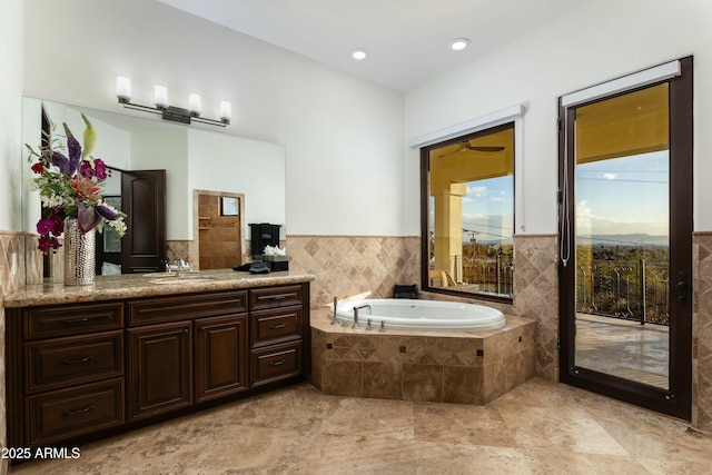 full bath with a wainscoted wall, a garden tub, and vanity