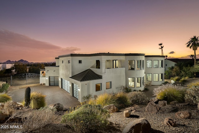 view of front facade featuring a garage, fence, metal roof, and stucco siding