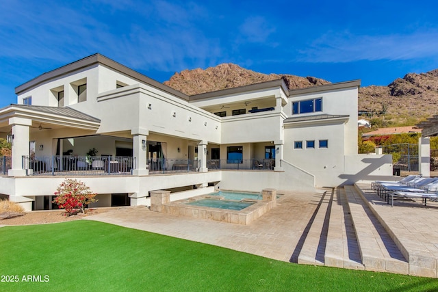 back of house featuring an in ground hot tub, a standing seam roof, a patio area, and stucco siding