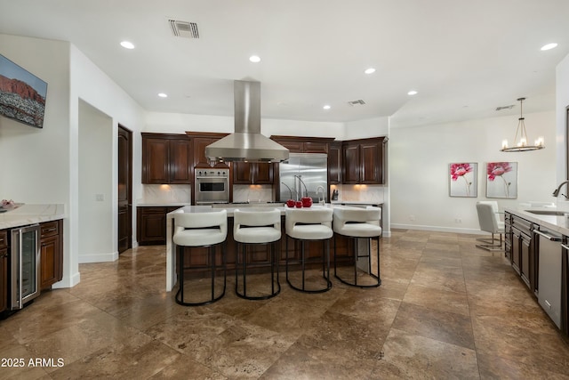 kitchen featuring tasteful backsplash, visible vents, wine cooler, island exhaust hood, and stainless steel appliances