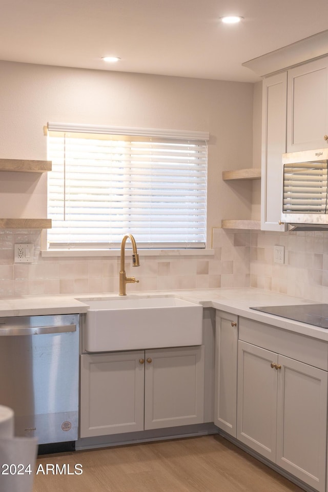 kitchen featuring sink, light hardwood / wood-style flooring, stainless steel dishwasher, backsplash, and gray cabinets