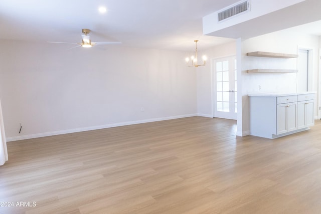 unfurnished living room featuring ceiling fan with notable chandelier and light wood-type flooring