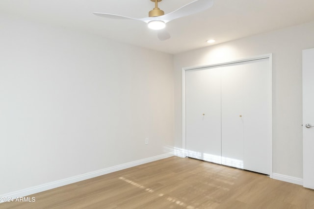 unfurnished bedroom featuring ceiling fan, a closet, and light wood-type flooring