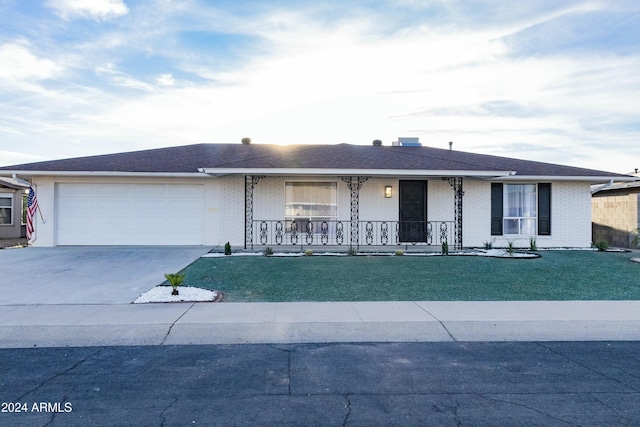 single story home featuring covered porch, a garage, and a front yard