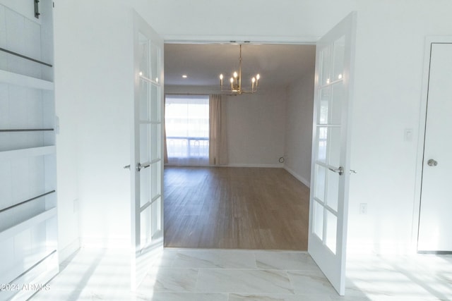 unfurnished dining area with light wood-type flooring, french doors, and a chandelier