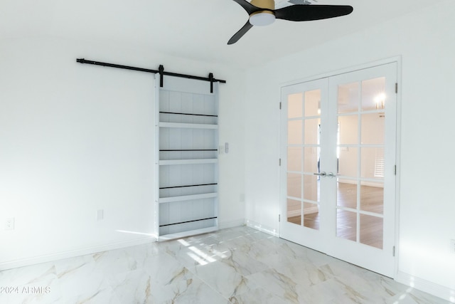 unfurnished room with french doors, a barn door, and ceiling fan