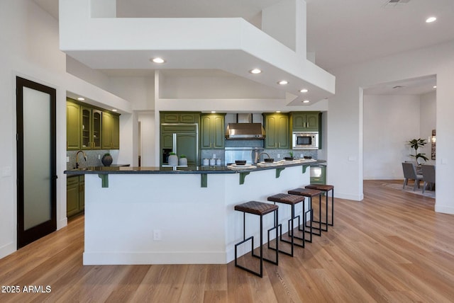 815 E County Down Dr, Chandler, AZ 85249 - kitchen with dark countertops, built in appliances, light wood-type flooring, a kitchen bar, and green cabinets