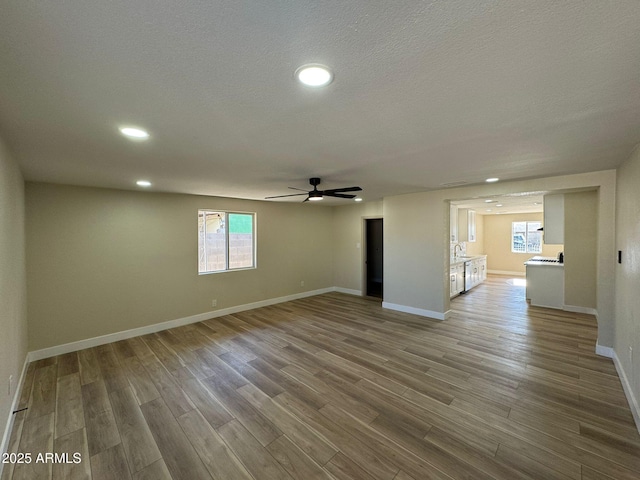 unfurnished room with ceiling fan, wood-type flooring, sink, and a textured ceiling