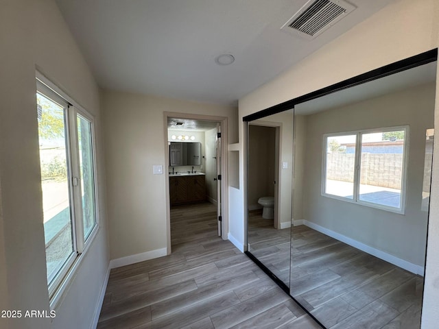 unfurnished bedroom with hardwood / wood-style flooring, connected bathroom, and a closet