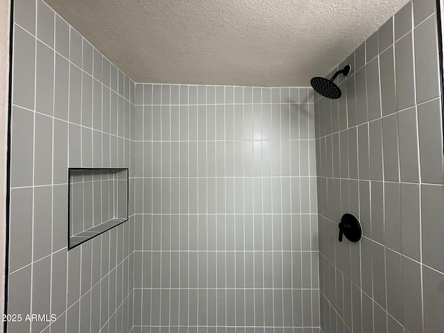 bathroom featuring a tile shower and a textured ceiling