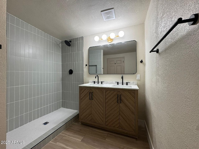 bathroom featuring a tile shower, vanity, and a textured ceiling