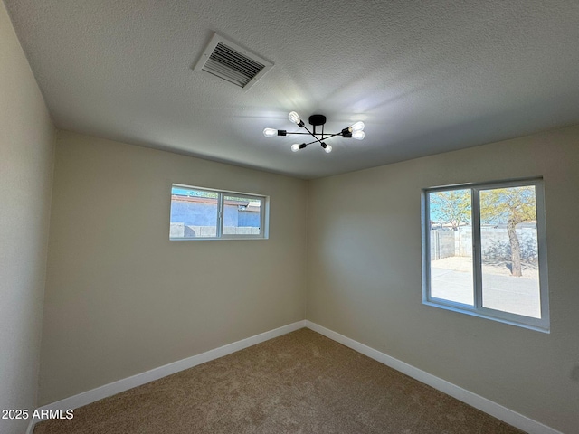 carpeted spare room featuring a notable chandelier