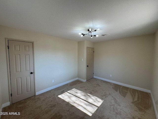 spare room with an inviting chandelier and carpet