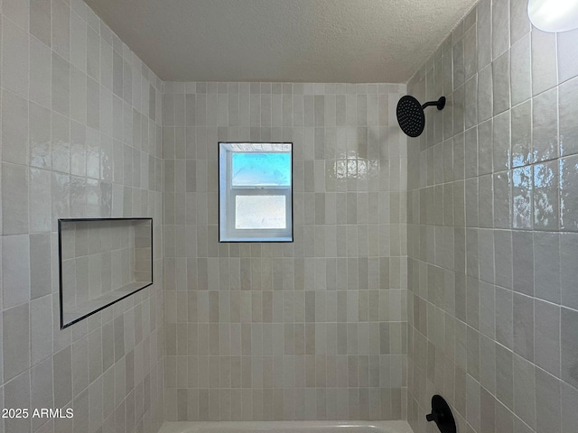 bathroom with tiled shower / bath combo and a textured ceiling