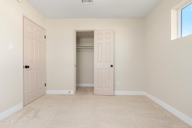 unfurnished bedroom with light colored carpet and a closet