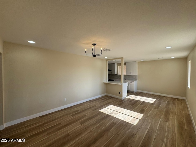 unfurnished living room featuring dark hardwood / wood-style flooring and an inviting chandelier