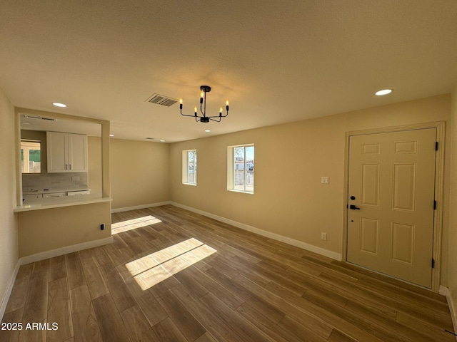 unfurnished living room with a notable chandelier and wood-type flooring