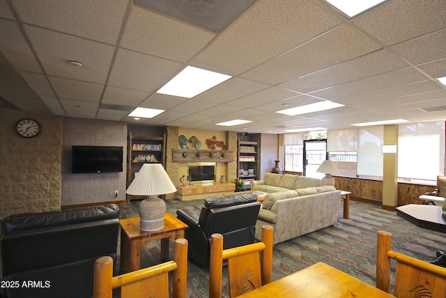 living room featuring carpet flooring, a drop ceiling, and wooden walls