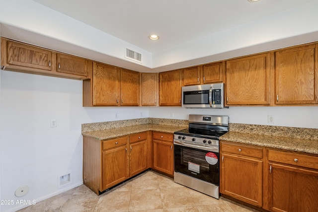 kitchen with light stone counters, appliances with stainless steel finishes, and light tile patterned flooring