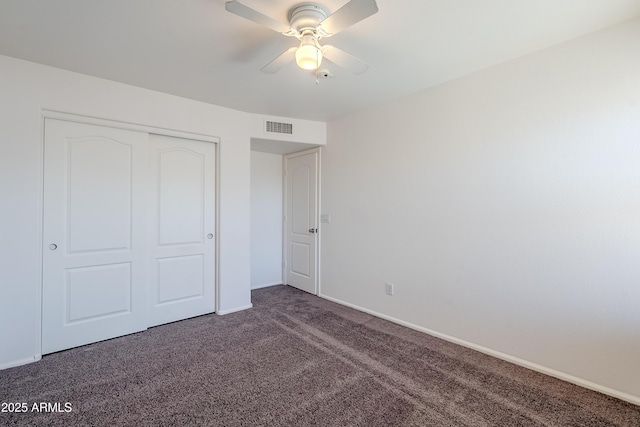 unfurnished bedroom with dark carpet, a closet, and ceiling fan