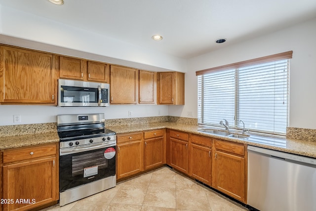 kitchen with sink, light tile patterned flooring, stainless steel appliances, and light stone countertops