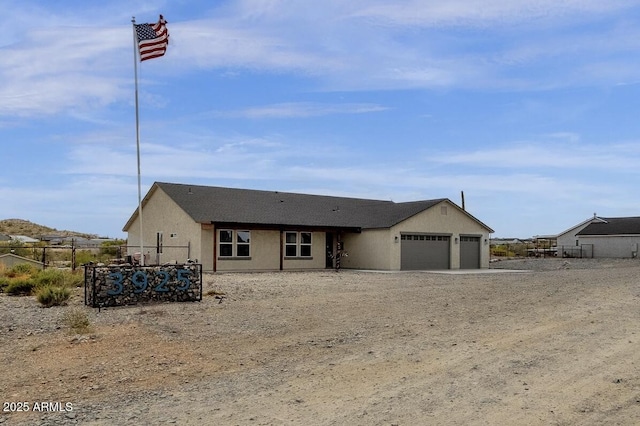 single story home with stucco siding, fence, and a garage