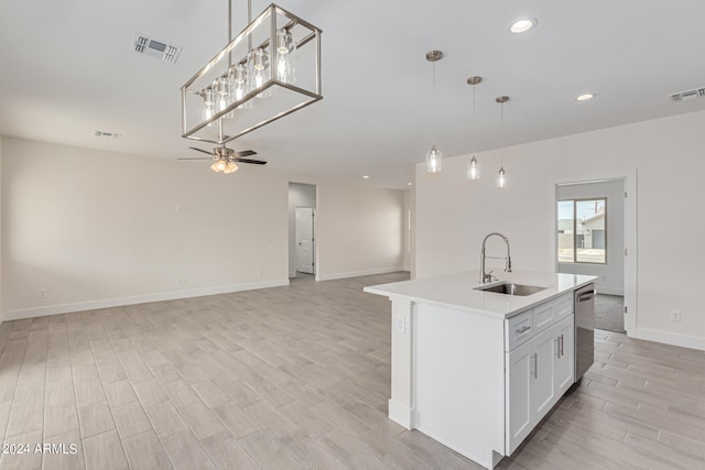 kitchen with pendant lighting, a center island with sink, sink, and white cabinetry