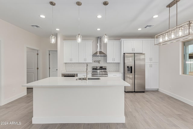 kitchen with stainless steel appliances, hanging light fixtures, sink, and wall chimney range hood