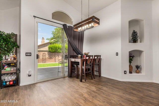 dining space with baseboards, a chandelier, wood finished floors, and vaulted ceiling