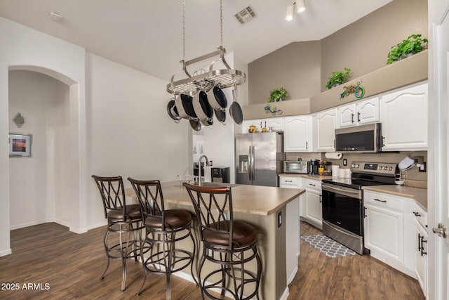 kitchen with visible vents, high vaulted ceiling, dark wood-type flooring, white cabinets, and appliances with stainless steel finishes