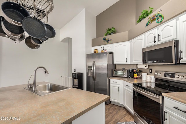 kitchen with a sink, white cabinetry, lofted ceiling, and stainless steel appliances